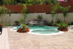 free-form-design-with-white-safety-grip-coping-spa-deck-pavers-and-rock-waterfall