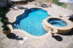 free-form-pool-with-raised-spa-tan-bullnose-brick-coping-paver-decking-and-medium-gray-plaster