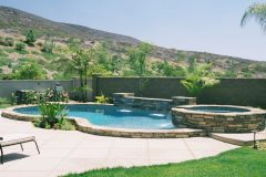 free-form-raised-pool-with-ledgerstone-quartzite-coping-raised-spa-sheer-descent-waterfalls-and-colored-concrete-deck